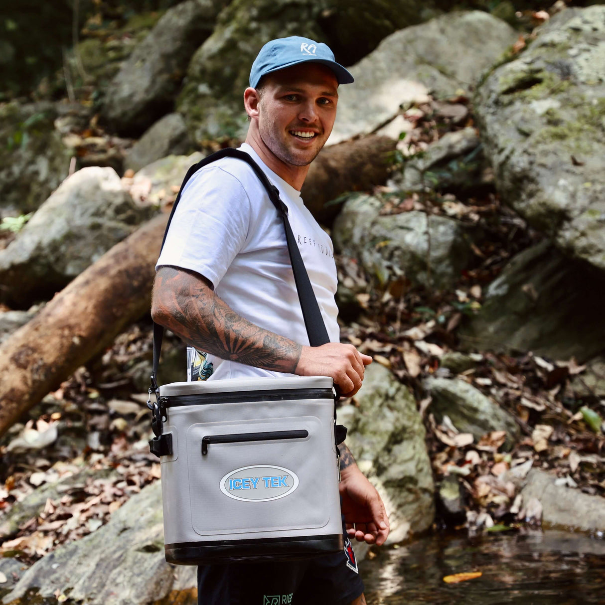 Man holding a cooler box in a rocky outdoor setting