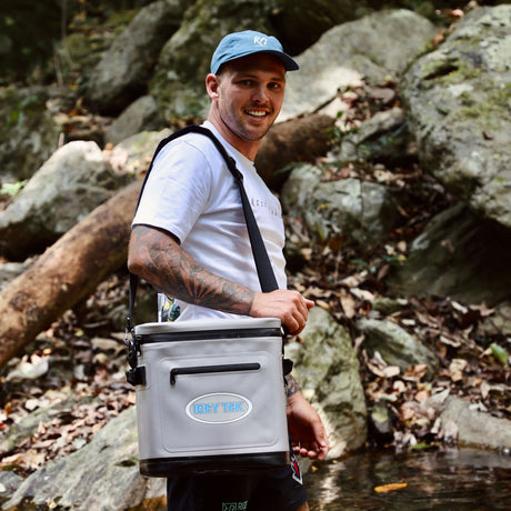 Man holding a cooler box in a rocky outdoor setting