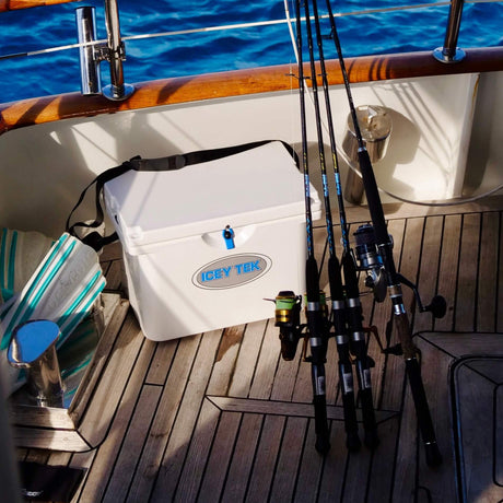 Fishing rods and tackle box on a boat deck with water in the background